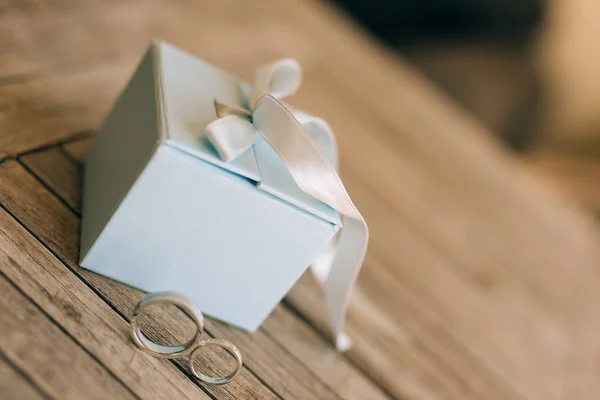 Trauringe auf einer hellen Holzstruktur in einer blauen Schachtel. Hochzeitsfeier — Stockfoto