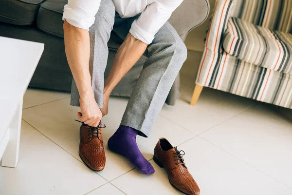 The man in gray slacks and a purple dress socks brown shoes with