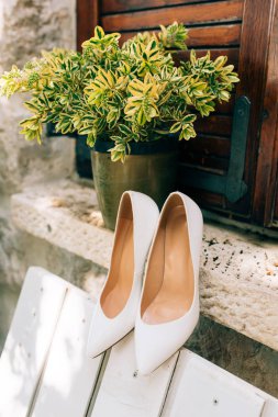 Beyaz bir Bank ve backgrou çiçekler beyaz gelin ayakkabıları