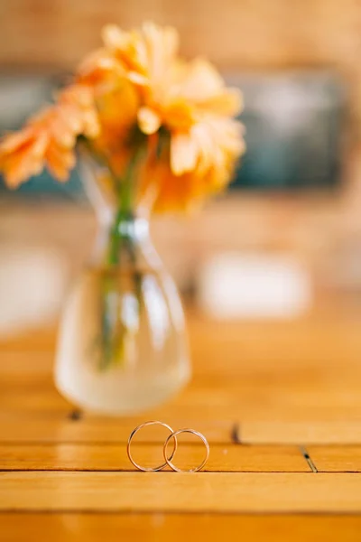 Anillos de boda sobre un fondo de jarrones de flores de gerberas. Boda j — Foto de Stock