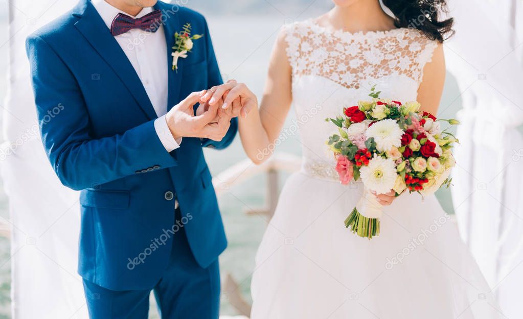 The groom dresses a ring on the finger of the bride at a wedding