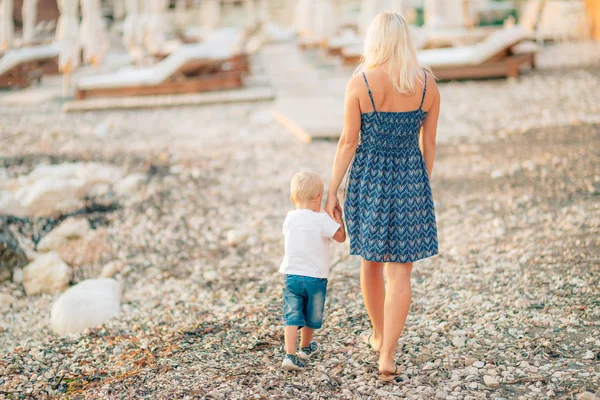 Ibu dan anaknya berjalan tangan di sepanjang pantai dari kerikil — Stok Foto