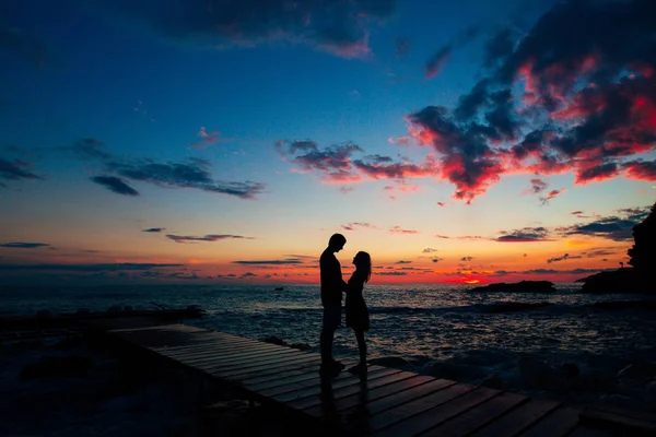 Σιλουέτα του ένα νιόπαντρο ζευγάρι στη θάλασσα στο ηλιοβασίλεμα. Γάμος στην — Φωτογραφία Αρχείου
