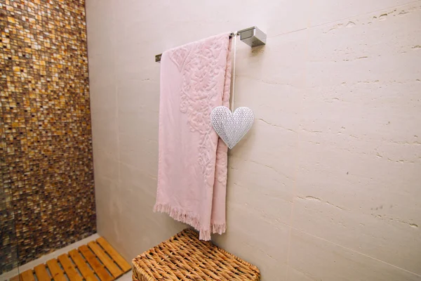 A pink towel is dried in the bathroom on the heated towel rail.