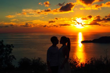 Bir yeni evli çift gün batımında denizde silüeti. İçinde düğün