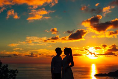 Bir yeni evli çift gün batımında denizde silüeti. İçinde düğün