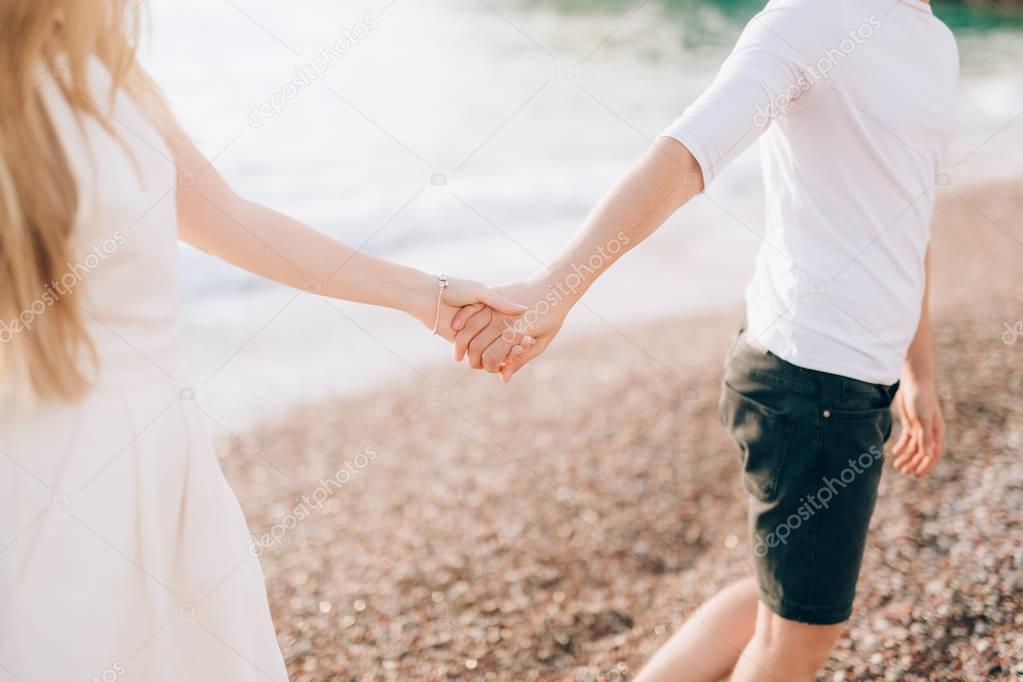 Newlyweds hold hands on the sea. Couple holding hands. Wedding i