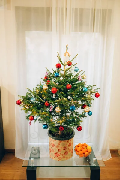 Malý vánoční stromek v květináči, zdobené koule, girlandy — Stock fotografie