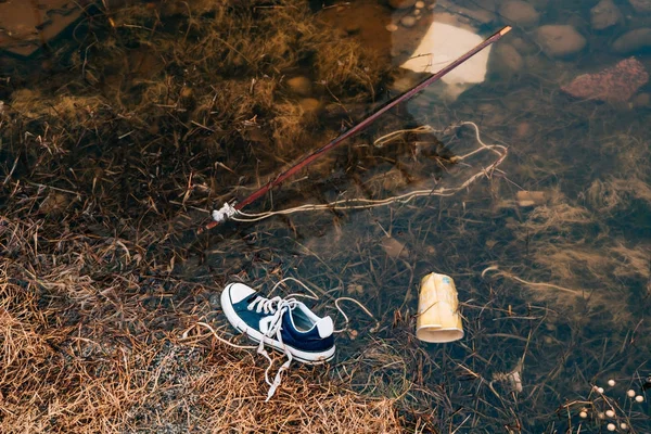 被污染的海滩运动鞋在河里游泳。河上的垃圾 — 图库照片