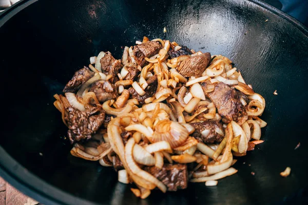 Cooking plov in the cauldron. Only meat and onions in a cauldron — Stock Photo, Image