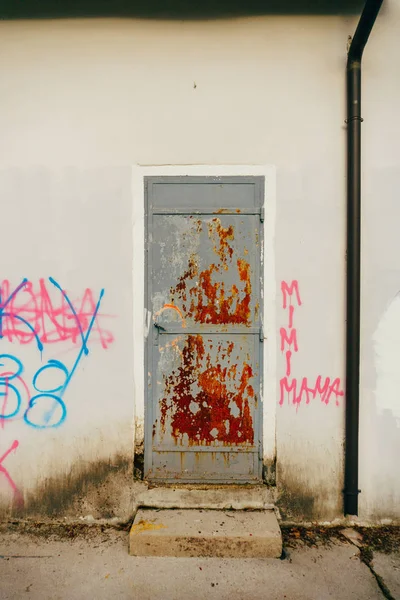 Gray metal entrance door in red rust, white wall — Stock Photo, Image