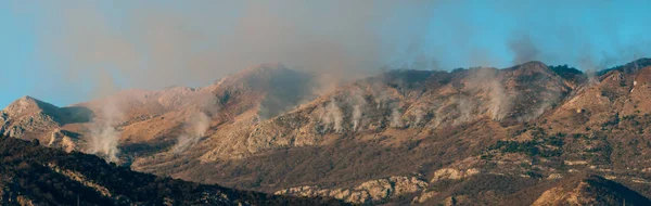 Fire in the mountains in the afternoon. Smoke over the mountains