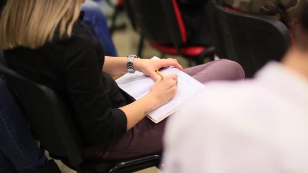 Το κορίτσι κάνει σημειώσεις σε ένα σημειωματάριο στα γόνατά της. Περιγράμματα στο — Αρχείο Βίντεο
