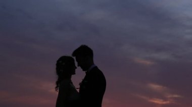 Yeni evliler günbatımı gökyüzüne karşı silüeti. Ben düğün