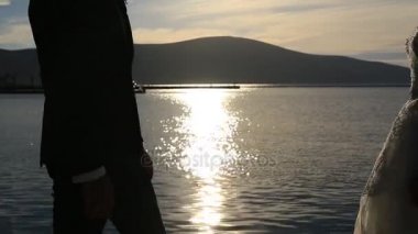 Bir yeni evli çift gün batımında denizde silüeti. İçinde düğün