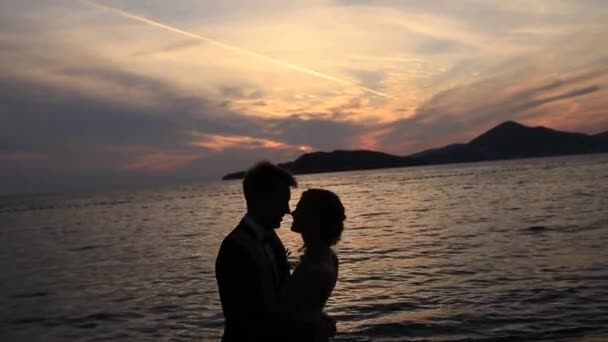 Silhueta de um casal recém-casado no mar ao pôr-do-sol. Casamento em — Vídeo de Stock