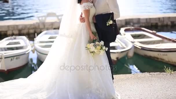 Brudgummen omfamnar den bruden båt förtöjning. Bröllop i Montenegro — Stockvideo