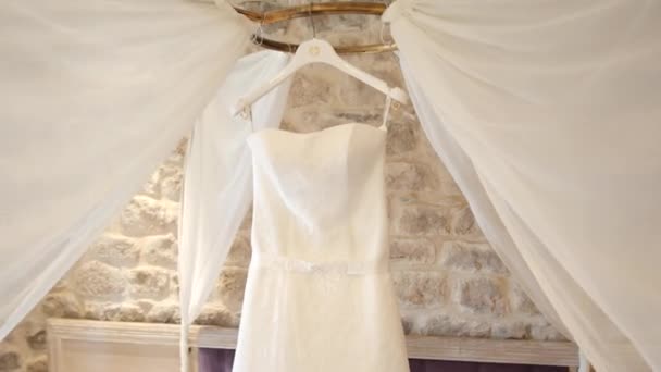 El vestido de novia de la novia cuelga sobre la cama. Colecciones o — Vídeo de stock