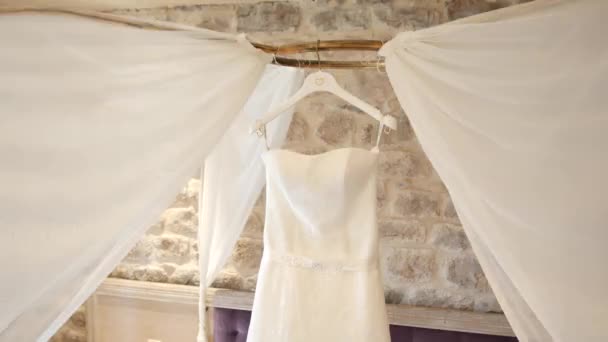 El vestido de novia de la novia cuelga sobre la cama. Colecciones o — Vídeos de Stock