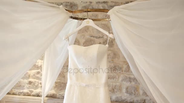 The wedding dress of the bride hangs over the bed. Collections o — Stock Video