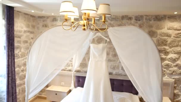 Весільна сукня нареченої звисає над ліжком. Колекції — стокове відео