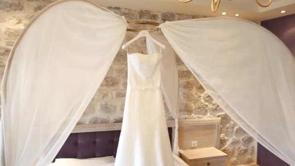 Az esküvői ruha a menyasszony az ágy fölött lóg. O gyűjtemények — Stock videók
