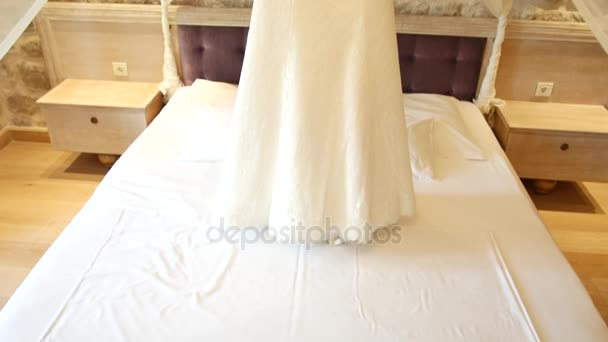 El vestido de novia de la novia cuelga sobre la cama. Colecciones o — Vídeo de stock