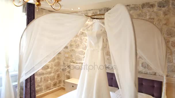 Svatební šaty nevěsty visí nad postelí. O sbírky — Stock video