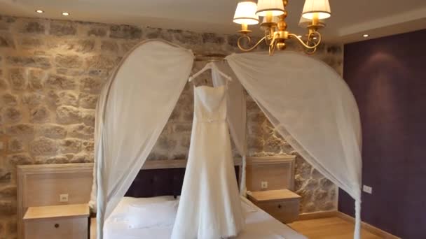 The wedding dress of the bride hangs over the bed. Collections o — Stock Video