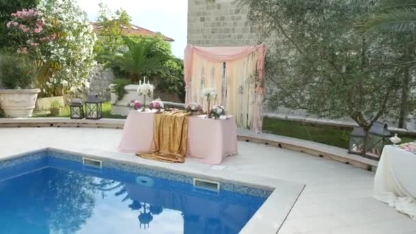 Una mesa en el banquete de bodas cerca de la piscina. Decoración de boda — Vídeos de Stock