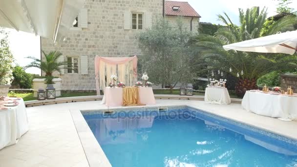 Een tabel op de bruiloft in de buurt van het zwembad. Bruiloft decoratie — Stockvideo