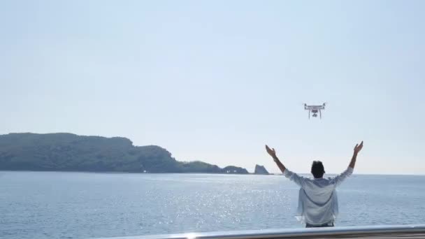 Een man op een jacht op de zee lanceert een drone. Een drone vliegt over — Stockvideo