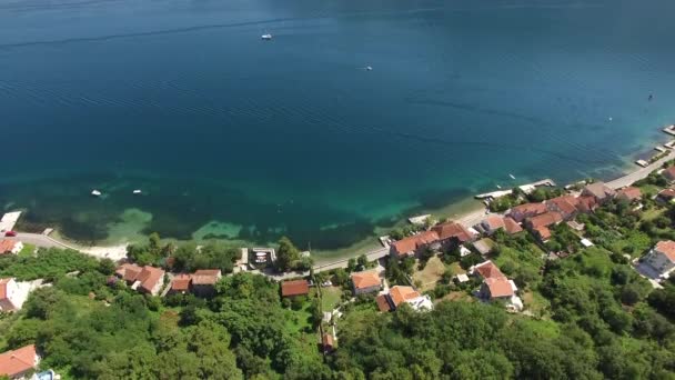 Bir iskele ve Petrovac kasaba kıyı konut evleri ile şehir kumlu plaj. Havadan görünümü — Stok video