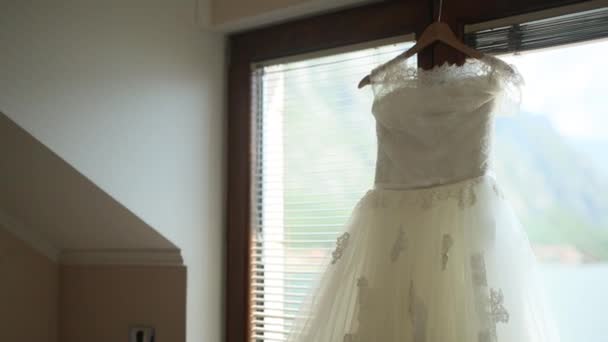 O vestido de noiva pendura na cornija na janela . — Vídeo de Stock