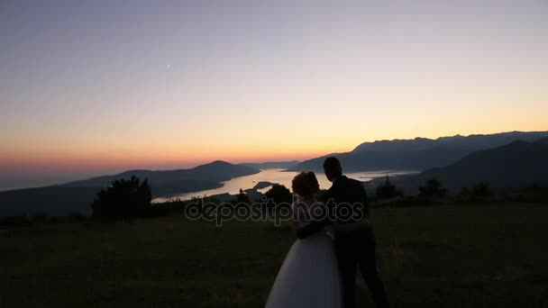 Silhouet van een jonggehuwde paar in de bergen bij zonsondergang. Wedd — Stockvideo