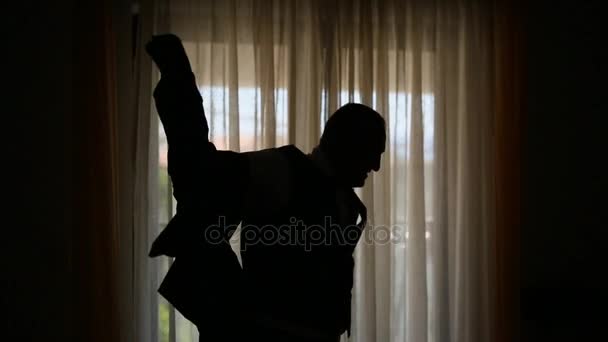 Silhouette d'un homme en arrière-plan d'une fenêtre habillant son j — Video