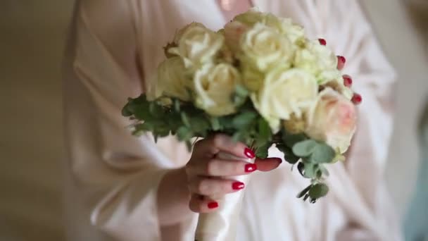 Brudbukett med rosor och eukalyptus i händerna på bruden — Stockvideo