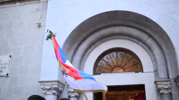 Bandera de Serbia ondeando frente a la iglesia en Kotor — Vídeos de Stock