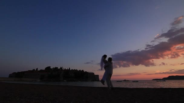 Silueta de una pareja recién casada en el mar al atardecer. Boda en — Vídeo de stock