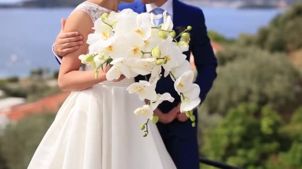 Bouquet da sposa di orchidee nelle mani della sposa, che abbracciano — Video Stock