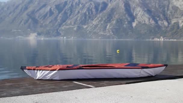 Kajak ligt op de oever. Houten steiger. Baai van Kotor in Montenegro — Stockvideo