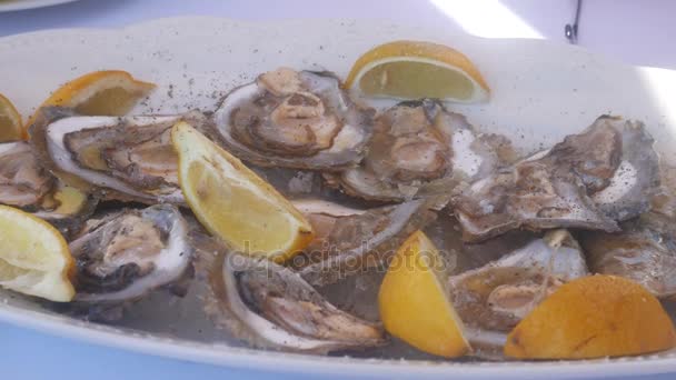 Mussels in a plate with lemons in restaurant. — Stock Video