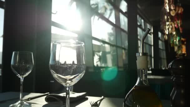 Εκτυφλωτικό φως του ήλιου σε ένα άδειο ποτήρι. Γυαλιά σε ένα τραπέζι σε ένα εστιατόριο — Αρχείο Βίντεο