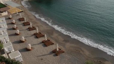 Şezlong ve şemsiyeleri sahilde. Karadağ plajları