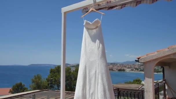 The brides dress flutters in the wind on the balcony, against t — Stock Video