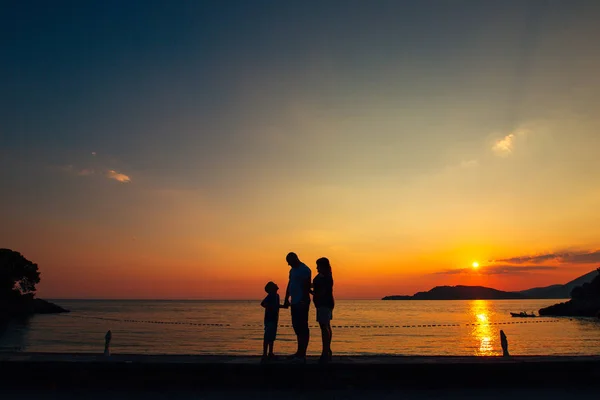 Silhueta de pais com uma criança no mar. Família na praia i — Fotografia de Stock