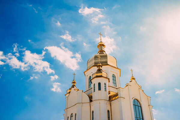 Church with golden domes against a blue sky with clouds.