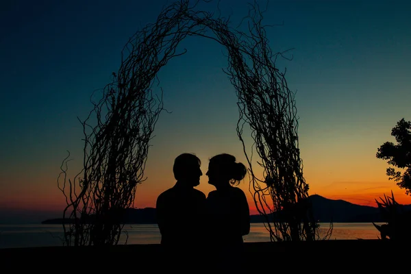 Silueta de una pareja recién casada en el fondo del sol poniente — Foto de Stock