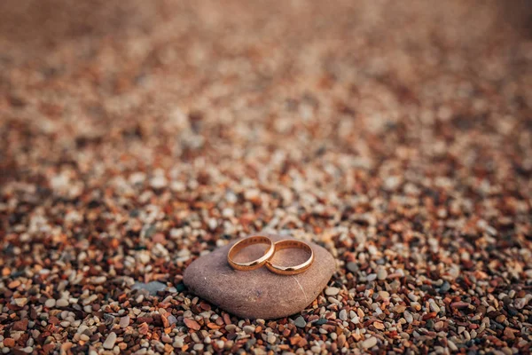 Anillos de boda de recién casados en guijarros de playa — Foto de Stock