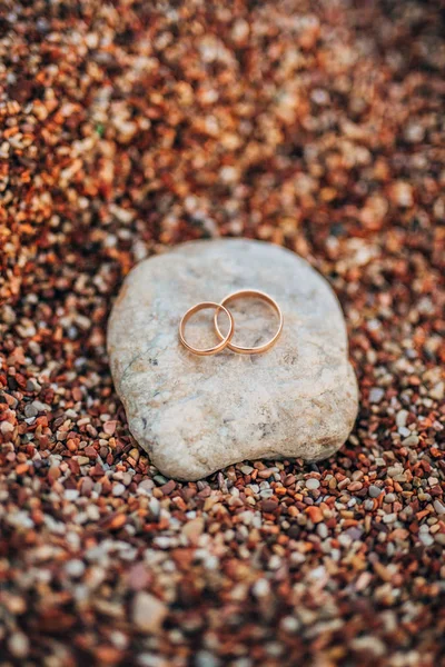 Anéis de casamento de recém-casados em seixos de praia — Fotografia de Stock